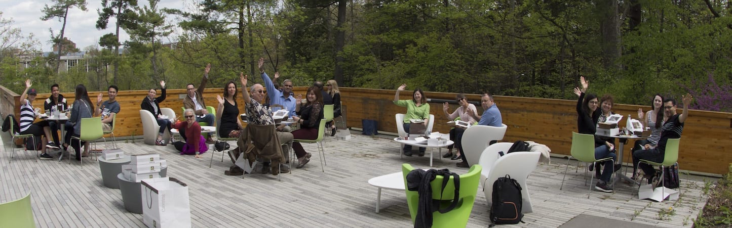 Photo of CIHF staff and affiliates sitting at modernist tables next to a forest