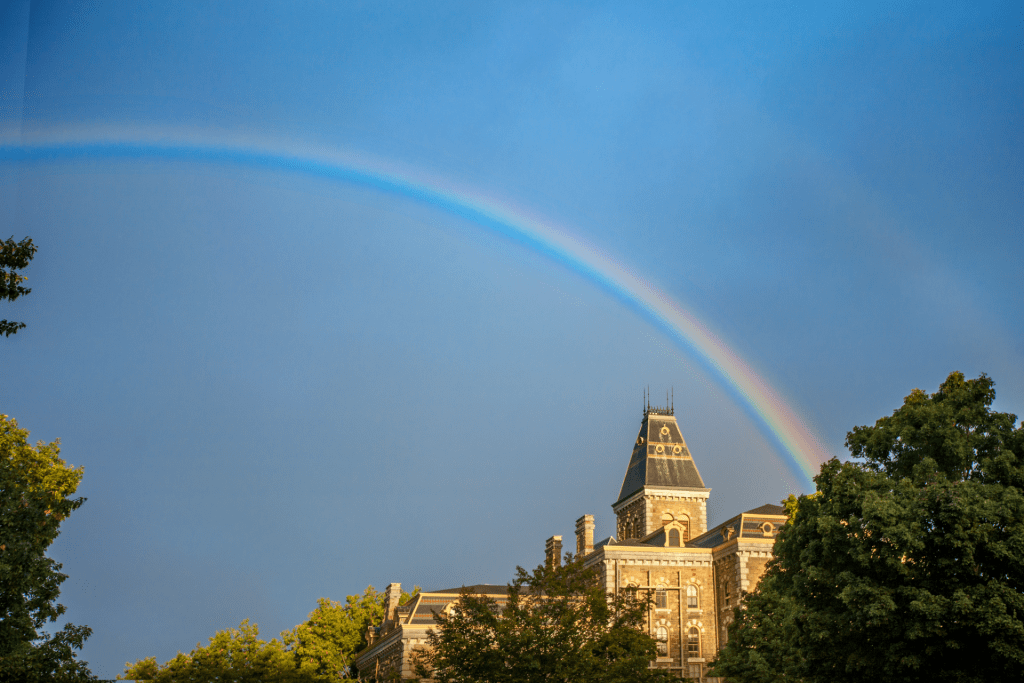 image of cornell campus with a rainbow above it with rainbow above it